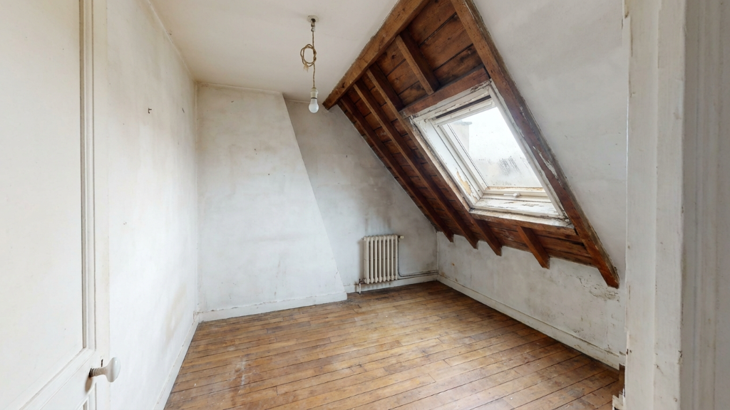 Raw attic room with exposed beams and skylight