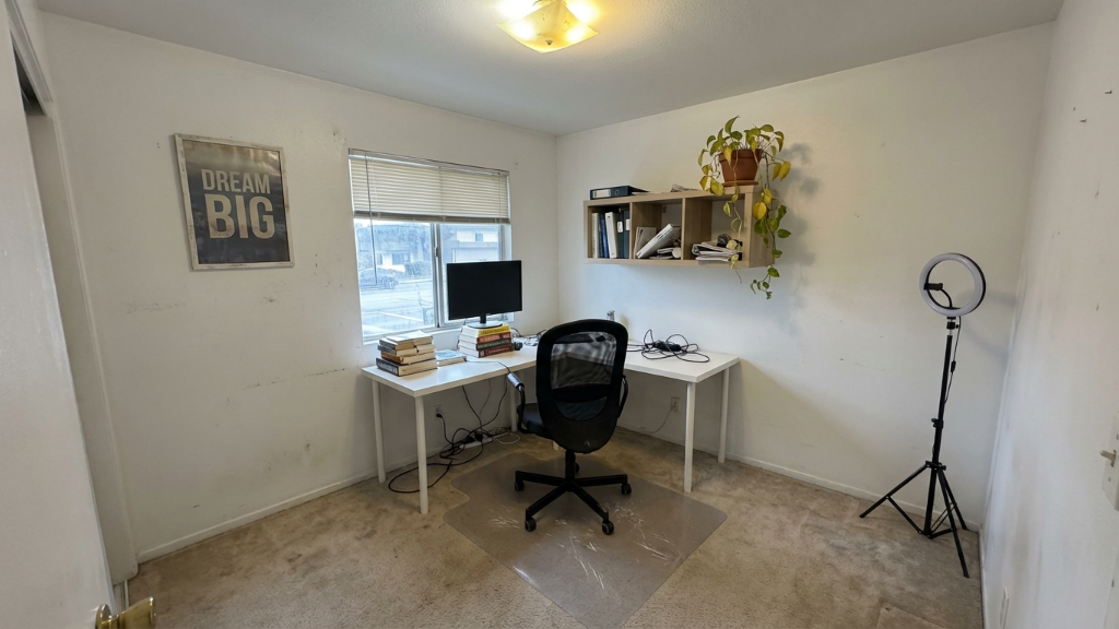 Sparse home office with white IKEA desks, office chair, ring light, and Dream Big poster