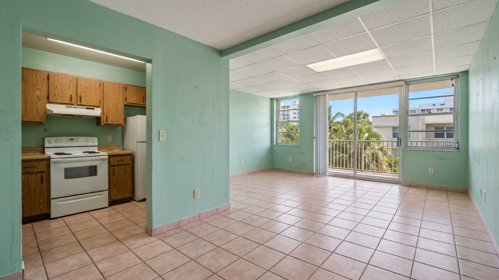 Empty rental studio with mint green walls, pink tile floor, drop ceiling, and dated oak kitchenette